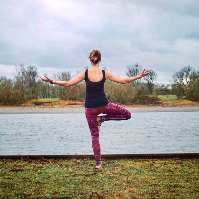 Eine Person in Yogapose am Rhein